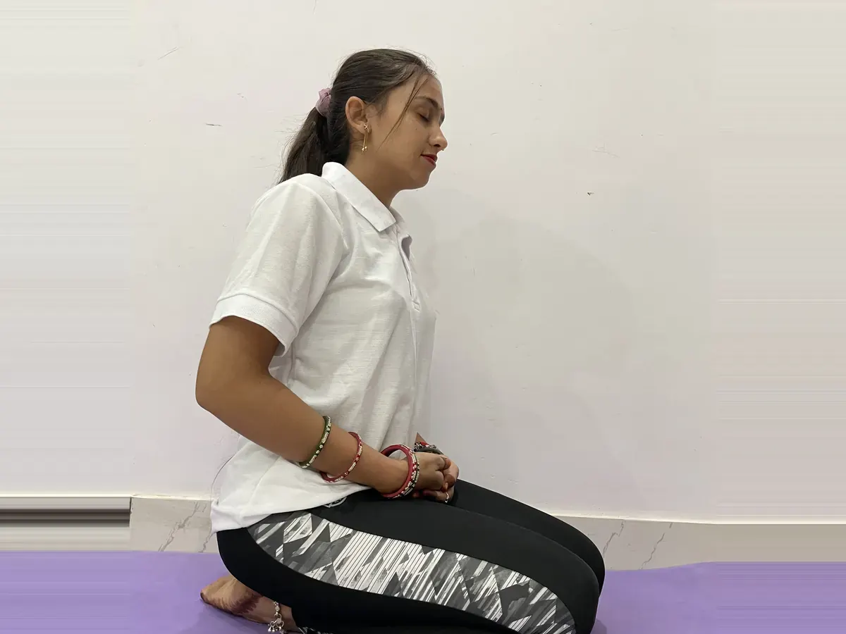 Latika sitting in Vajrasana on a purple yoga mat